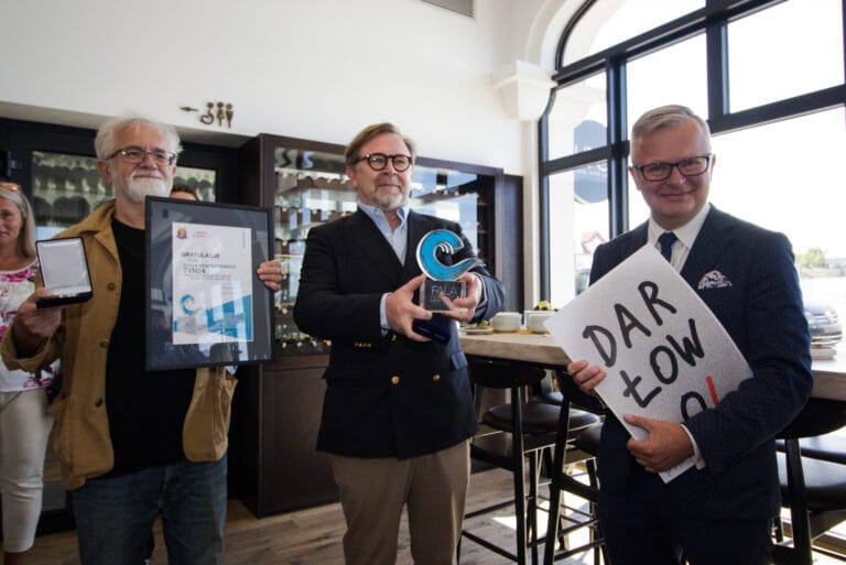 Grupa mężczyzn z nagrodami w eleganckich strojach.