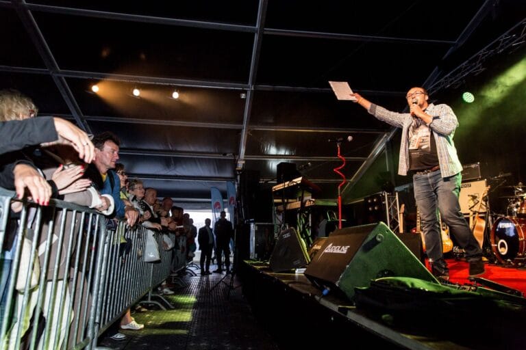 Koncert w namiocie, mężczyzna prowadzi wydarzenie