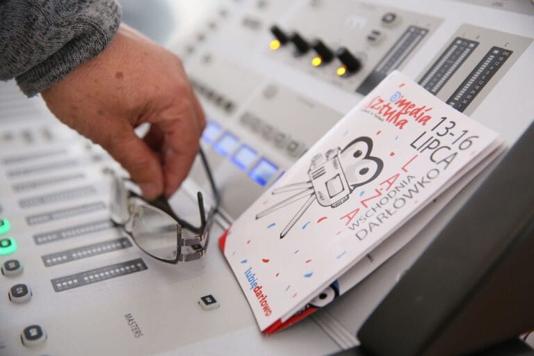 Ręka przy mikserze audio i ulotka festiwalu filmowego