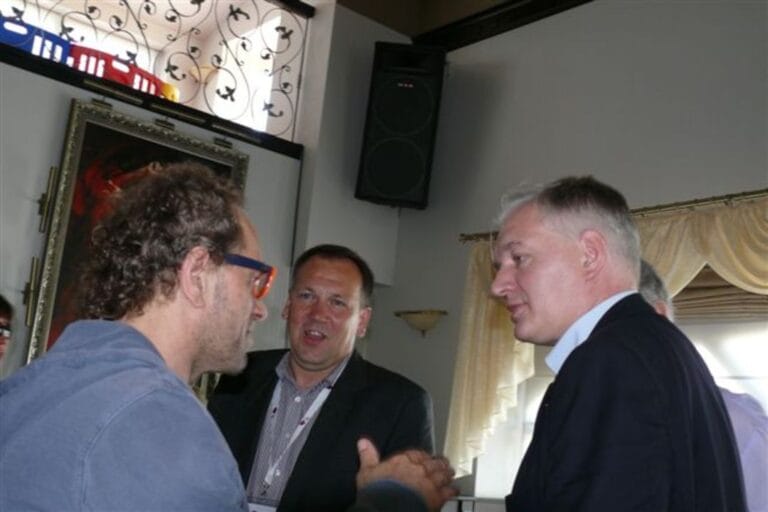 Trzy osoby rozmawiają w eleganckim pomieszczeniu