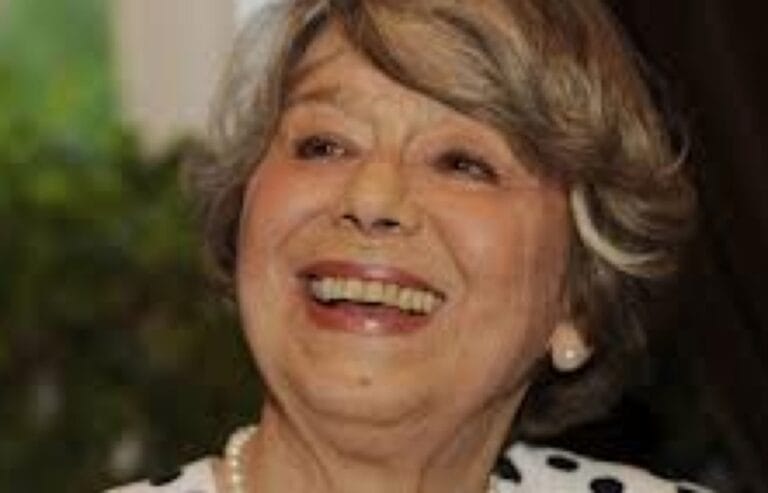 Uśmiechnięta starsza kobieta z krótkimi, siwymi włosami.