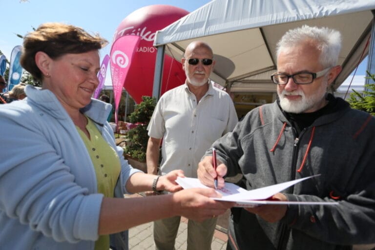Osoba podpisująca dokument na świeżym powietrzu.
