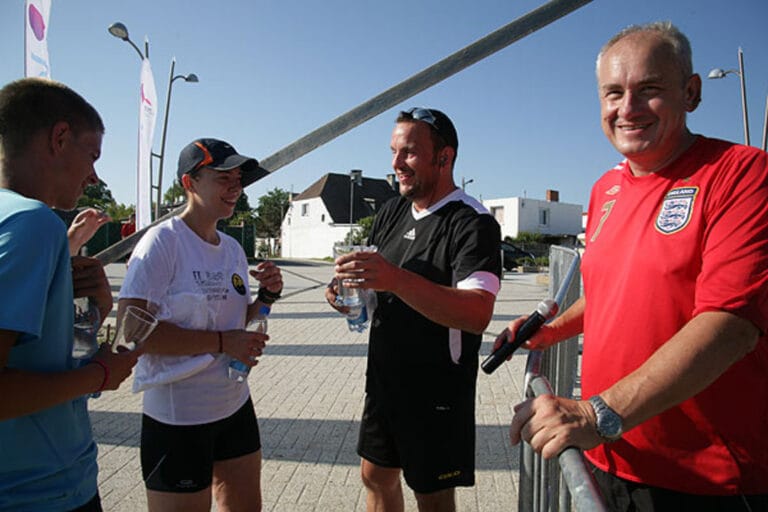 Grupa ludzi rozmawia i pije wodę na zewnątrz.