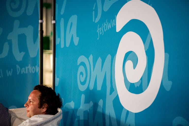 Mężczyzna przy niebieskim banerze z napisem festiwal