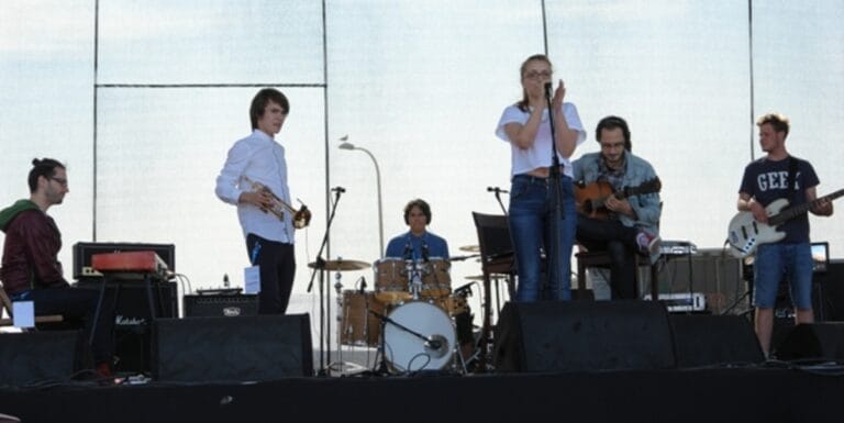 Zespół muzyczny występuje na scenie na świeżym powietrzu.