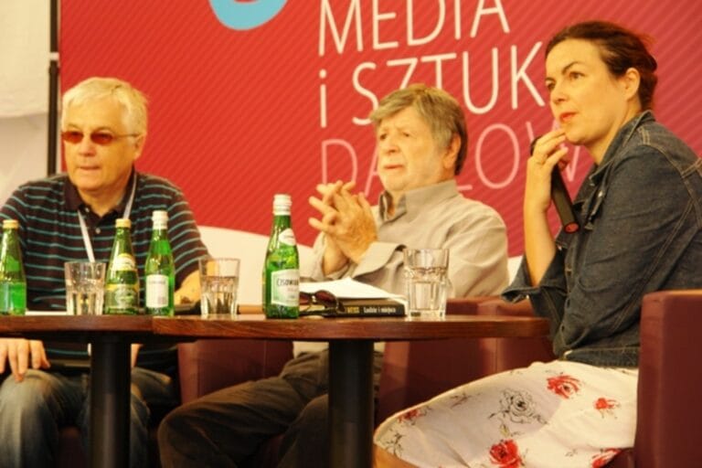 Osoby przy stole dyskusyjnym z butelkami wody.