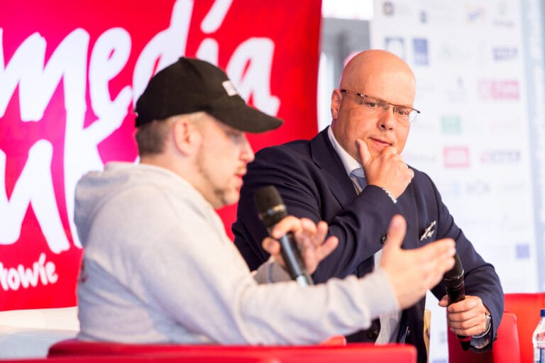 Dwóch mężczyzn rozmawia na konferencji z mikrofonami.