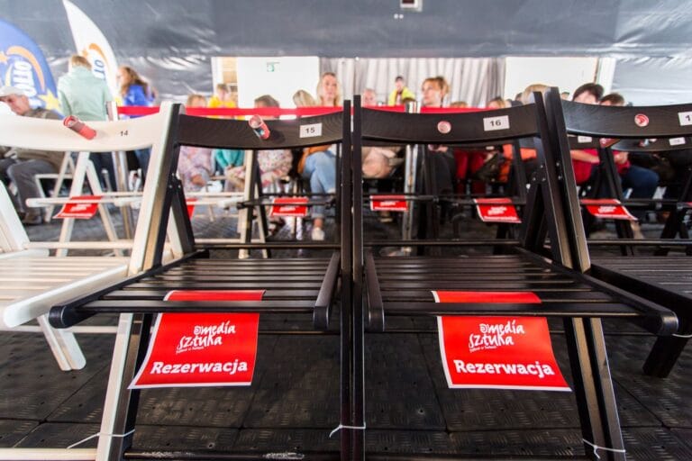 Zarezerwowane miejsca na wydarzeniu, ludzie w tle.