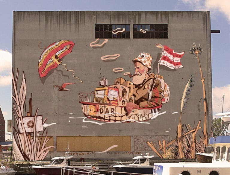 Mural żeglarza na szarym budynku z flagą 'peace'.