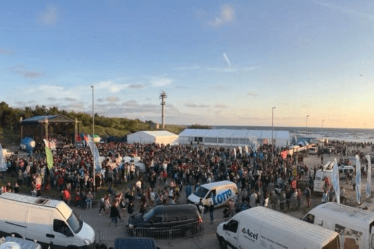 Tłum na festiwalu nad morzem o zachodzie słońca.