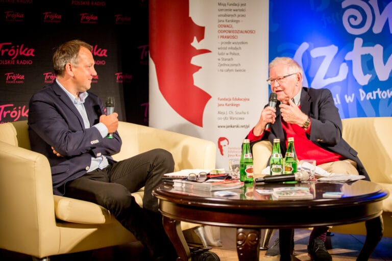 Dwóch mężczyzn rozmawia w studiu radiowym.