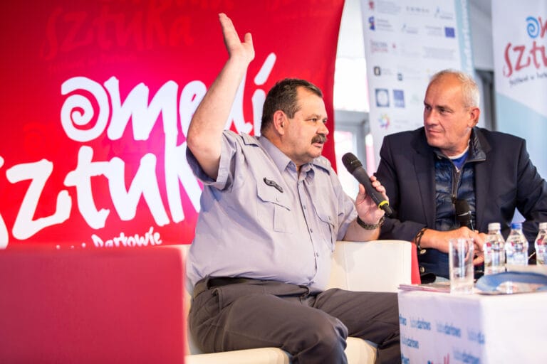 Dyskusja dwóch mężczyzn z mikrofonami na festiwalu.