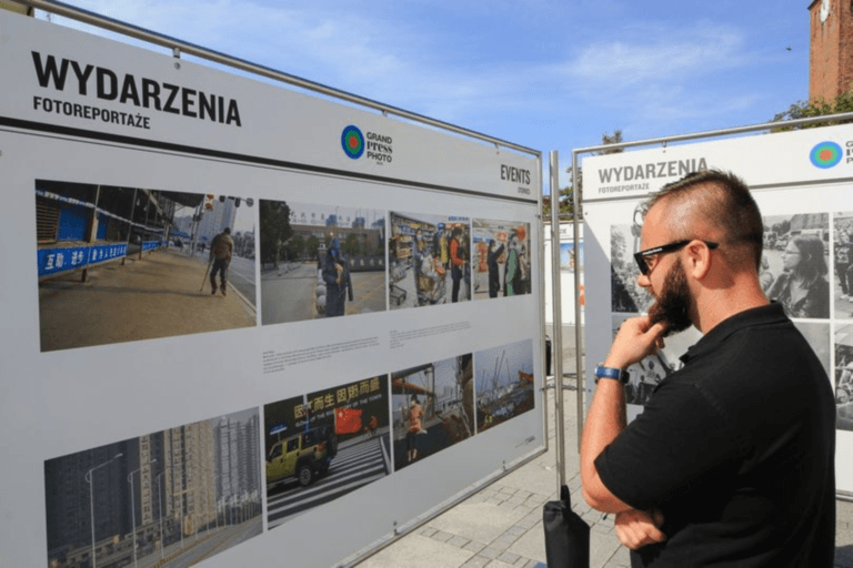 Mężczyzna ogląda wystawę fotoreportaży na zewnątrz.