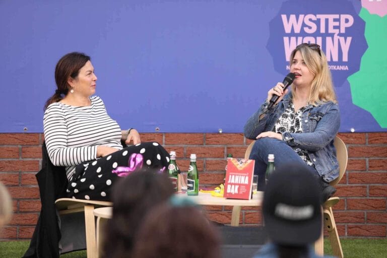 Dwie kobiety rozmawiają na scenie z mikrofonem.
