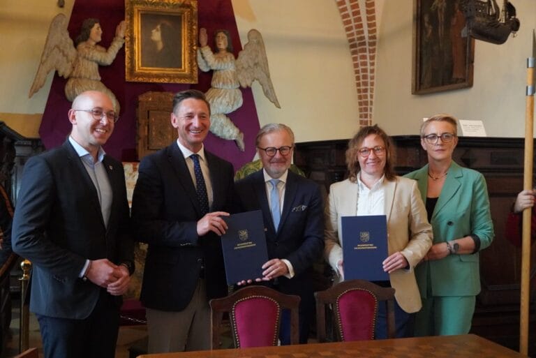 Grupa osób z dokumentami w historycznym wnętrzu.