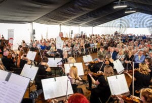 Koncert orkiestrowy w namiocie, licznie zgromadzona publiczność.