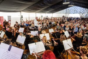Koncert orkiestry przed dużą publicznością w namiocie.