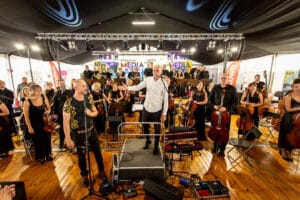 Koncert orkiestry w namiocie, muzycy na scenie.