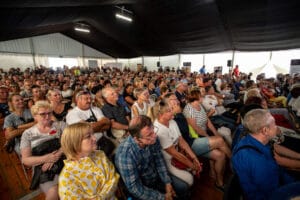 Tłum ludzi na spotkaniu w namiocie konferencyjnym.