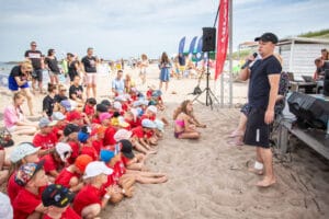 Dzieci siedzą na plaży z animatorem.