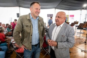 Dwóch mężczyzn rozmawia na evencie w namiocie.