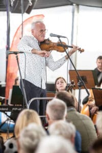 Muzyk grający na skrzypcach przed publicznością.