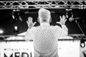 Mężczyzna gestykuluje na scenie podczas występu muzycznego.