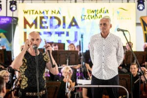 Konferencja medialna z orkiestrą w tle.