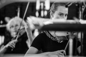 Skrzypaczki podczas koncertu orkiestry, czarno-białe zdjęcie.