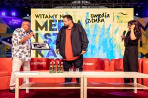 Trzy osoby na scenie, wręczanie nagrody, media sztuka.