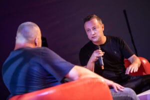 Dwóch mężczyzn w rozmowie na scenie.