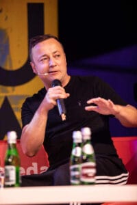 Osoba mówiąca do mikrofonu na czerwonej kanapie.