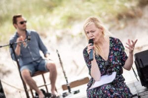 Koncert na plaży, kobieta śpiewa z mikrofonem.