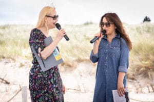 Dwie kobiety rozmawiają na plaży z mikrofonami.