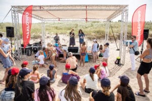 Ludzie na plaży uczestniczą w wydarzeniu pod namiotem.
