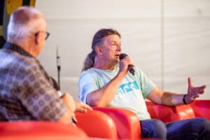 Dwóch mężczyzn rozmawia na scenie z mikrofonami.