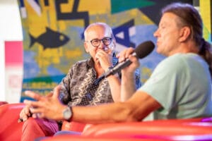 Dwóch mężczyzn dyskutuje na scenie z mikrofonem.