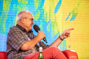 Mężczyzna z mikrofonem na scenie, uśmiechający się.