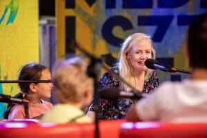 Kobieta i dzieci rozmawiają w studio radiowym.