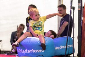 Dziecko wskazuje palcem, siedząc na niebieskim pufie.