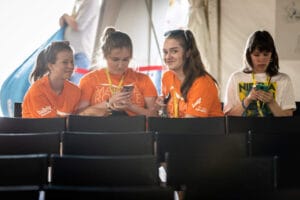 Cztery osoby siedzą z telefonami na widowni.