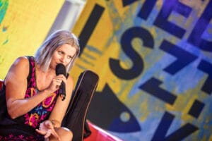 Osoba z mikrofonem na scenie konferencyjnej.