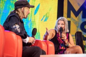 Dwoje ludzi rozmawia na scenie z mikrofonami.