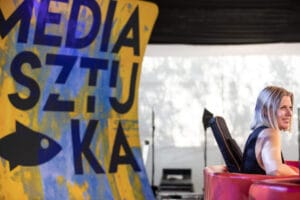 Kobieta przy stoisku z napisem MEDIA SZTUKA