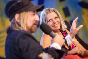 Dwoje ludzi rozmawia na scenie z mikrofonami.