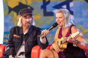 Muzyk z gitarą i mikrofonem na scenie.