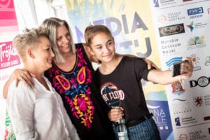 Trzy osoby robią selfie na wydarzeniu.