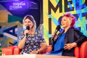 Dwie kobiety rozmawiają w studiu, trzymają mikrofony