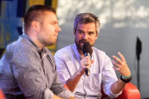 Dwóch mężczyzn rozmawia na scenie z mikrofonem.