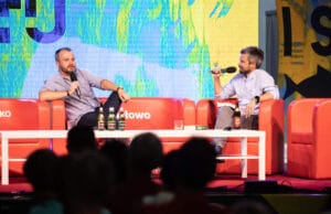 Dwóch mężczyzn rozmawia na scenie z mikrofonami.